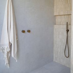 a white towel hanging on the side of a shower