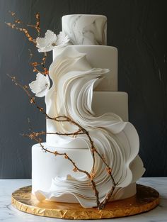 a three tiered cake with white icing and flowers on the top, sitting on a gold platter