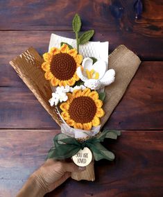 a bouquet of sunflowers and daisies on a brown paper bag with a tag