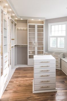 an empty walk in closet with white cabinets and drawers