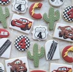 decorated cookies with cars, trucks and cactuses on a white tablecloth for a birthday party