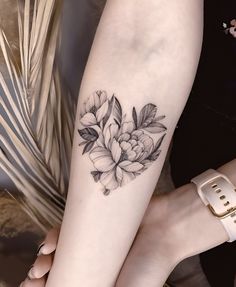 a woman's leg with a flower tattoo on her left forearm and the other arm