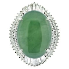 A substantial and bold ring featuring a natural 23.22 carat jadeite jade. It has an even green color and is semi-translucent allowing light to emanate from the stone. It is accented by 3.46 carats of round and baguette-cut diamonds set in a stylish pattern around the jade. Hand fabricated in platinum and ready to be worn! Ring Size 6.25 Imperial Jade, Bold Rings, Gold Cocktail Ring, Gold Cocktail, Diamond Cocktail Rings, 1920s Art Deco, Jade Ring, Baguette Cut Diamond, Platinum Ring