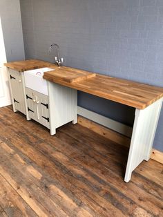 a sink and counter in a room with wood floors on one side and white cabinets on the other