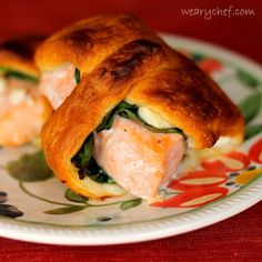 two pastries with salmon and spinach are on a floral plate, one is cut in half