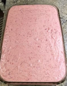 a pink cake in a glass pan on a counter