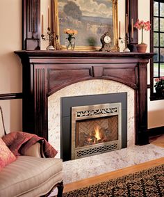 a living room with a fire place in the center and a painting on the wall