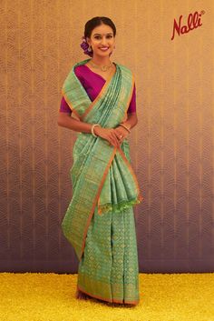 This beautiful saree is draped in a traditional style with front waist pleats followed by a pleated pallu draped around the back, pulling the pallu end that's placed in the front in a stylized way. Saree is paired with a contrast three-fourth blouse in a deep neck pattern to match the look. Saree styling is done with a pair of earrings, necklace, bangles, and a finger ring in a similar color tone. #Saree #Drapes #Women #Fashion #SareeStyles #Banarasi #Silk #Festive Nalli Silk Sarees, Saree Drapes, Kora Silk Sarees, Traditional Silk Saree, Patiala Salwar, Banarasi Saree