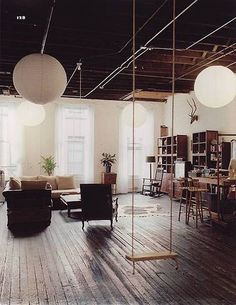 a living room filled with lots of furniture and hanging lights on the ceiling above it