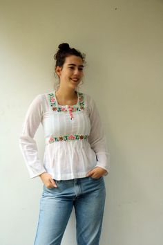 Beautiful vintage 70's Indian white blouse floral embroidered detailing in pink, yellow, blue, green and brown, cotton, long sleeves, five buttons down the bodice, high waist with a belt tied at the back for an adjustable fit, original tag intact, aside from minor signs of wear, including ultra-faint amber marking under the arms, otherwise good vintage condition clean, ready to wear.**Model is 5'8" and a size S/M for reference ** tag size: MApproximate size: S  - Please refer to the measurements Gamine Style, Pretty Blouses, High Waist Dress, Star Wars Shirts, Blouse Vintage, Embroidered Blouse, White Blouse, Vintage Cotton, Waist Dress