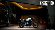 a motorcycle is parked in front of a wall with lights and a potted plant