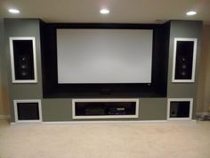 a large screen mounted to the wall in a home theater room with speakers on either side