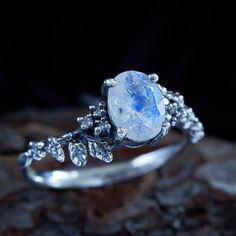 a close up of a ring with a stone in the middle and leaves around it