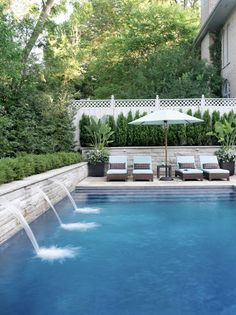 an outdoor swimming pool with lounge chairs and umbrellas in the middle, surrounded by greenery