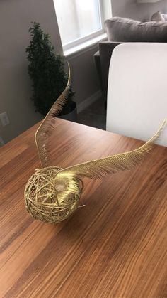 a golden bird sculpture sitting on top of a wooden table