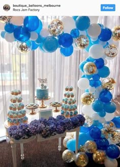 blue and white balloons are hanging from the ceiling above a table with desserts on it