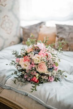 a bridal bouquet sitting on top of a bed next to pillows and pillow cases