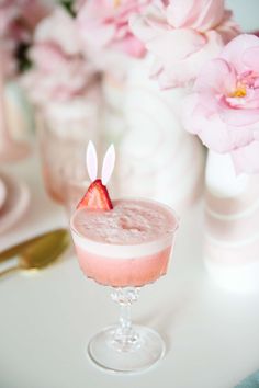 there is a small drink with strawberries in it on the table next to pink flowers