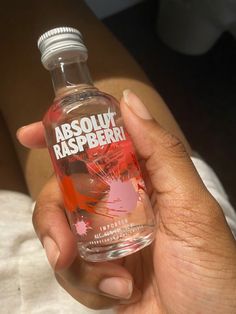 a person holding a bottle of absolu raspberry water in their hand