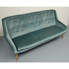 a green couch sitting on top of a gray floor