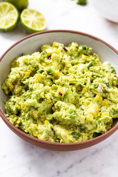 a bowl filled with guacamole next to limes