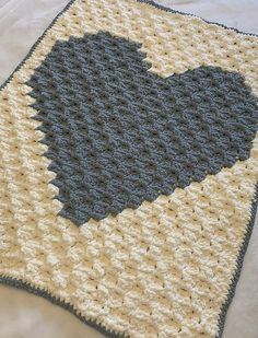 a crocheted blanket with a blue heart on the bottom and yellow border around it