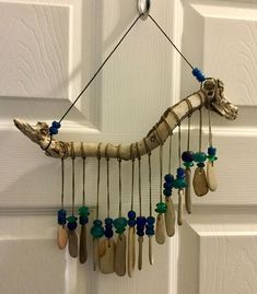 a giraffe made out of driftwood and beads hangs on a door handle