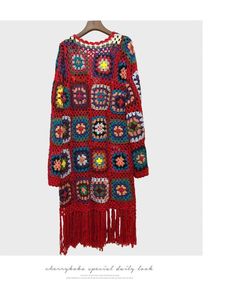 a crocheted dress with fringes and flowers on the shoulders is hanging from a hanger