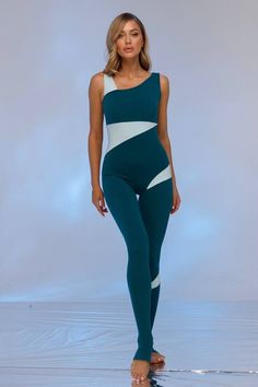 a woman in a green and white one piece swimsuit is standing on the beach