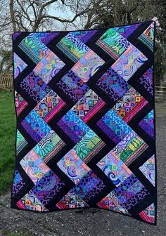 a colorful quilt hanging from the side of a tree