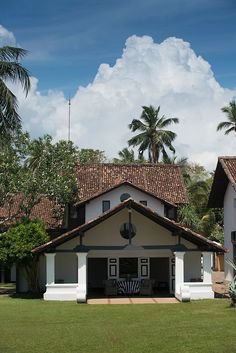 a white house sitting on top of a lush green field next to tall palm trees