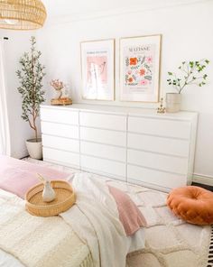 a bedroom with white furniture and pictures on the wall