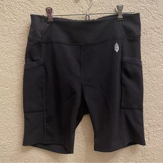 a pair of black shorts hanging up against a wall with the bottom pocket open and an emblem on it