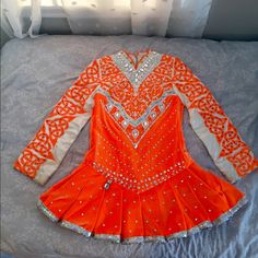 an orange and white dress is laying on a bed