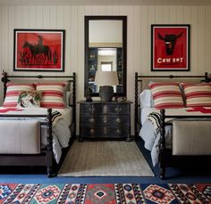 two beds in a room with pictures on the wall above them and rugs below