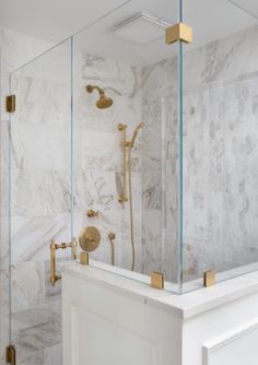 a bathroom with marble walls and gold fixtures on the shower head, tub, and toilet