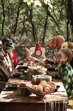 a group of people sitting at a table with masks on their faces and food in front of them