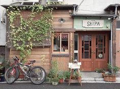 two bikes are parked in front of a building with vines growing on the side of it