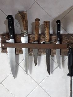 there are many knives hanging on the wall with each one's own knife holder