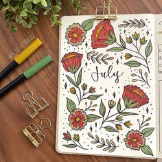 a clipboard with the word july written on it next to some office supplies and flowers