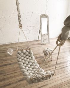 a chair made out of balls and chains on a wooden floor next to a mirror