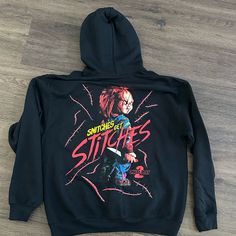 the back of a black hoodie with an image of a clown holding a knife