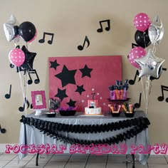 a party table with balloons, streamers and music notes on the wall behind it