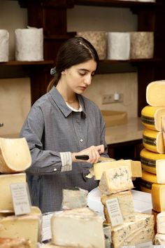 a woman standing in front of stacks of cheese