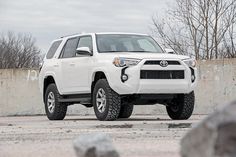 a white toyota 4runner is parked in front of a wall with graffiti on it