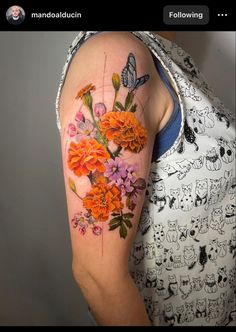 a woman's arm with flowers and butterflies painted on the back of her shoulder