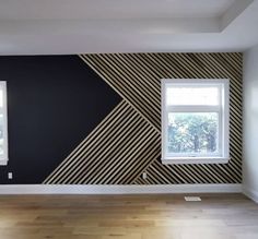 an empty room with black and white wallpaper, two windows and wood flooring