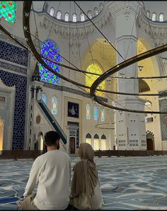 two people sitting on the ground in front of an ornate building with stained glass windows