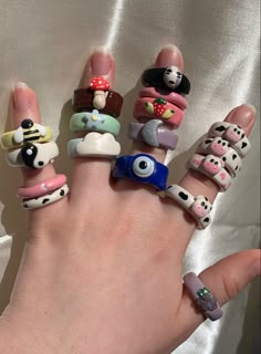 a person's hand with many different rings on it, all decorated in cartoon characters