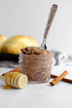 a glass jar filled with food next to cinnamon sticks